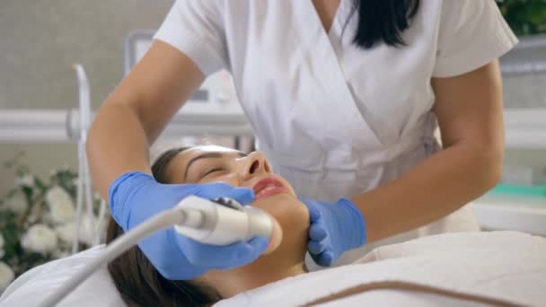 Gesichtspflege-Verfahren, Glück Client-Mädchen genießen Hautreinigung mit Hilfe von speziellen Gerät in den Händen des Meisters im Schönheitssalon — Stockvideo