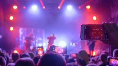 Rock festivali, elinde aletle bir sürü insan konserde video kaydı yapıyor.