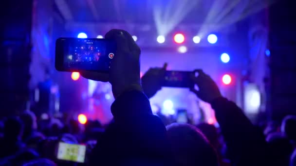 Música en vivo, multitud de fans con el teléfono celular en las manos en el concierto de rock en la iluminación del centro de atención — Vídeos de Stock