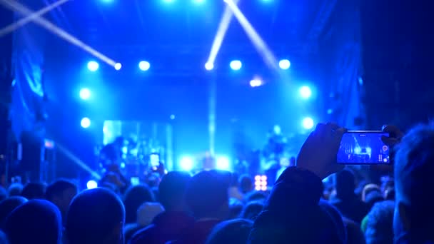 Entretenimiento nocturno, sesión de admirador en la actuación telefónica de la banda de rock en el escenario iluminado — Vídeos de Stock