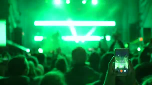 's nachts entertainment, veel mensen klappen en maken video op gadget bij concert in knipperende lichten — Stockvideo