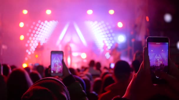 Nachtleven, fans mensen nemen foto 's op smartphone op rockconcert met heldere scène — Stockvideo