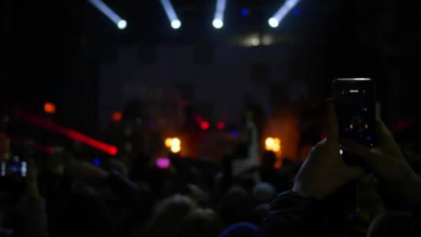 कूदने वाले प्रशंसकों और मोबाइल फोन का सिल्हूट रात में केंद्रित वीडियो दृश्य बनाता है — स्टॉक वीडियो
