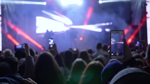 Skara fans med mobiltelefoner i vapen spelar in video av rockkonsert — Stockvideo