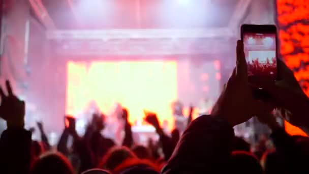 Rock event, donkere vormen van fans springen en zwaaien handen opnemen op mobiele telefoon van de prestaties live muziek — Stockvideo