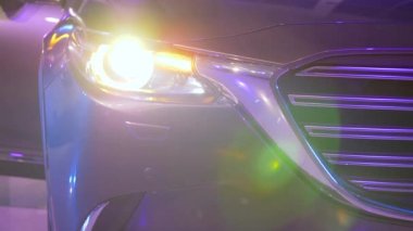 Araba farları parlak ışıkta yanıp sönüyor.