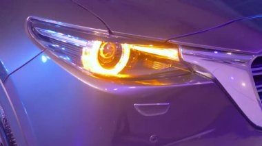 Motor fuarı, araba farları parlıyor.