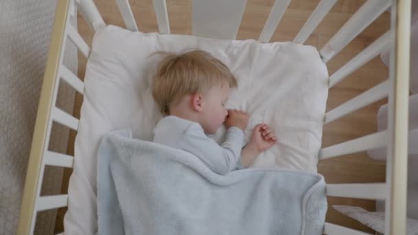 Милый ребенок сладко спит на подушке в своей кроватке, дети дневной сон восстанавливает нервную систему в ребенке — стоковое видео