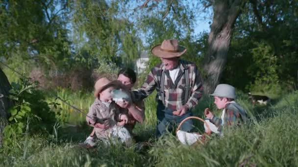 Family atmosphere, cheerful elderly woman with grandfather and grandchildren drink milk from glass can during family picnic and enjoy outdoor — Stock Video