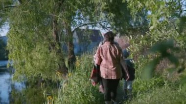 Kırsal kesimdeki aile, sağlıklı çocuk dedelerle el ele yürür, doğanın tadını çıkarır ve yabani çiçekler toplar.