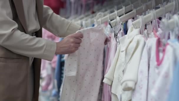Γυναίκα γονέας αγοράζει πλεκτά για το παιδί της σε ράφια καταστημάτων, close-up — Αρχείο Βίντεο
