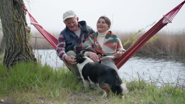 Lebensstil, fröhliche alte erwachsene Familienpaar umarmen lachen Ruhe Spaß zusammen in einer Hängematte am Fluss — Stockvideo