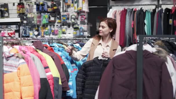 Shopaholic, mujer hermosa comprador recogiendo ropa de estantes de la tienda — Vídeos de Stock
