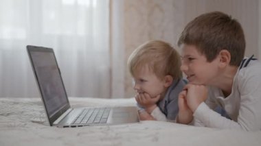 Modern teknolojiler, küçük kardeşler eğleniyor, sosyal ağlarda dizüstü bilgisayardan komik programlar izliyorlar.