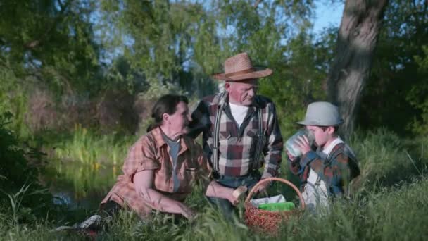 Jídlo venku, šťastní prarodiče a jejich milovaný vnuk vychutnat venkovní rekreaci — Stock video