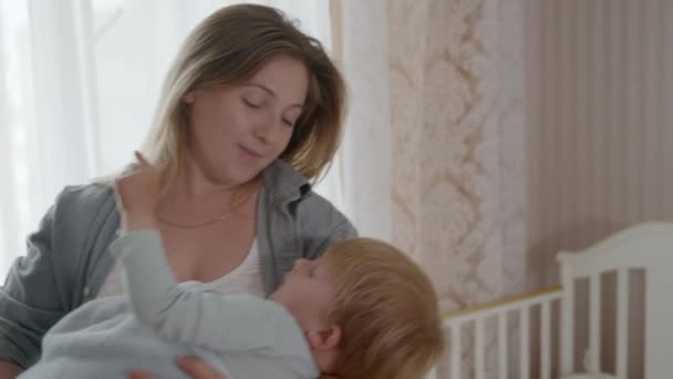 Anyaság, gyönyörű szerető nő remeg a karjaiban az ő kedves kis fiú gyermek, énekel neki altatódal a szobában — Stock videók