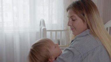 Çocuklarla ilişki, sevgi dolu mutlu kadın annelikten zevk alıyor ve yatmadan önce kucağında küçük şirin bir bebeğin kollarıyla sallanıyor.