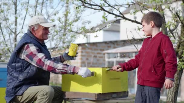 Πορτρέτο των χαρούμενων μελισσοκόμων, ένας ηλικιωμένος χαμογελαστός άνθρωπος και ο εγγονός του χαίρονται με την ολοκλήρωση των εργασιών με κυψέλες — Αρχείο Βίντεο