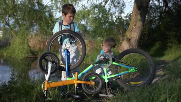 Atrativos meninos curiosos girar rodas e pedais de bicicleta ao ar livre na floresta — Vídeo de Stock