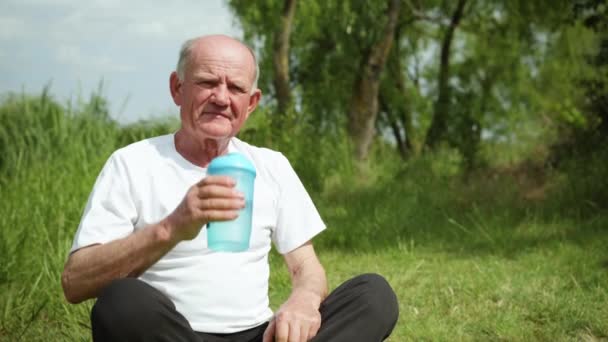 Portrét staršího zdravého muže pijícího čistou studenou vodu po sportování a meditaci — Stock video