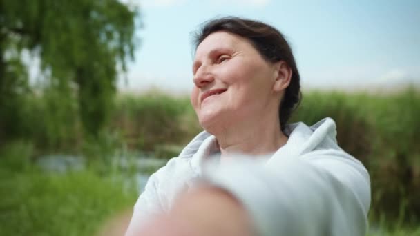 Anciana sonriente mujer conduce a cuidar de su salud y lleva un estilo de vida deportivo, anciana mujer se dedica a los deportes para apoyar la salud al aire libre — Vídeo de stock