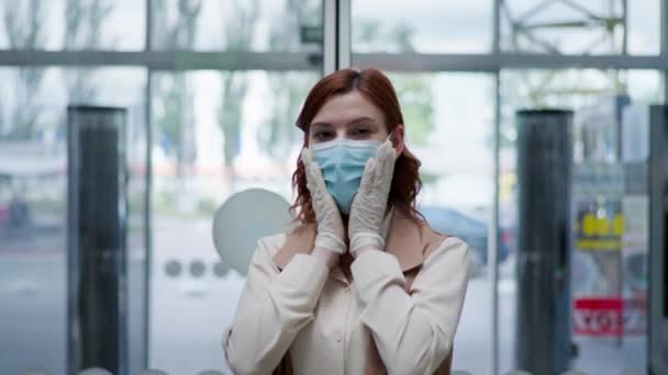 Retail, portret van jonge vrouw in handschoenen op medisch masker ter bescherming tegen coronavirus bij ingang van supermarkt — Stockvideo