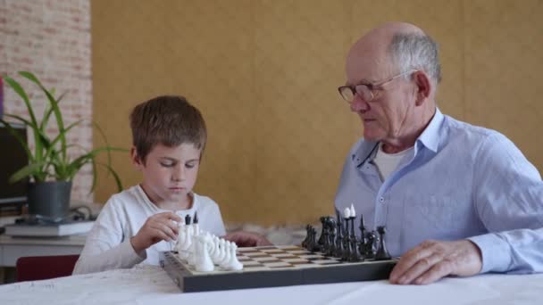 Jeux éducatifs, vieil homme attentionné dans des lunettes pour la vision joue à des jeux de société avec son petit-fils intelligent — Video