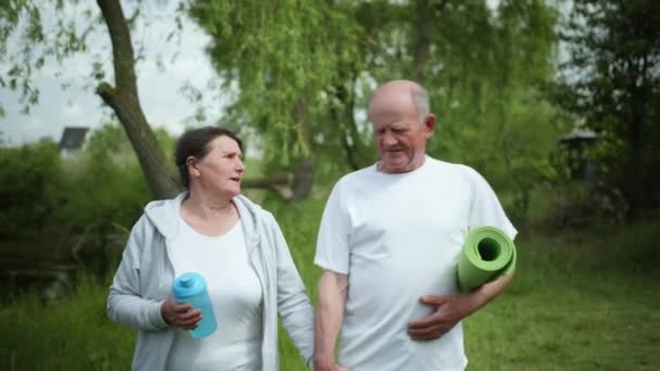 Stile di vita sano, uomini e donne anziani coppie prendono possesso delle mani dopo l'allenamento mattutino all'aperto vicino al fiume tra gli alberi — Video Stock