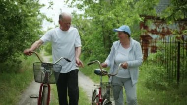 Yaşlı aile, yaşlı karı koca birlikte iyi vakit geçiriyorlar, bisiklet sürerken gülümsüyorlar ve sohbet ediyorlar.