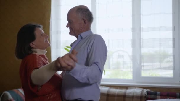 Mutlu aile, hayat dolu yaşlı çift orta yaşlı kadın ve erkek birlikte rahatlıyor evde dans ediyor yıldönümünü kutluyor şefkatin ve şefkatin tadını çıkarıyorlar. — Stok video