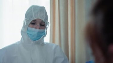 Salgın, tıbbi maskeli kadın doktor ve virüs ve enfeksiyondan korunmak için gözlük takan kadın koronavirüs belirtileri gösteren bir kadını muayene ediyor.