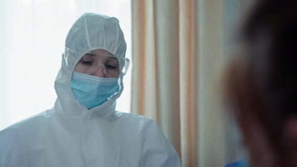 Pandemie, vrouwelijke arts met medisch masker en bril op bescherming tegen virus en infectie onderzoekt een vrouw met symptomen van coronavirus — Stockvideo