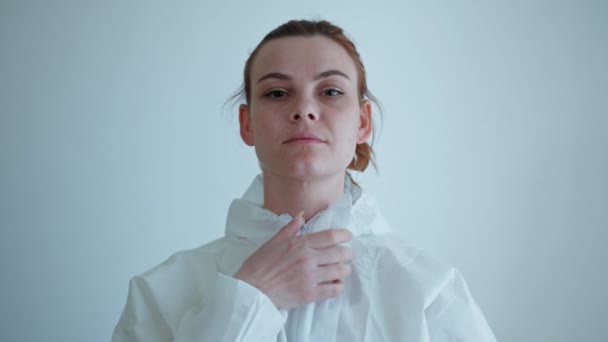 Женщина-врач, медицинский работник в защитном костюме, надевает перчатки, чтобы защитить от вируса и инфекции перед пациентом с болезнью или коронавирусом — стоковое видео
