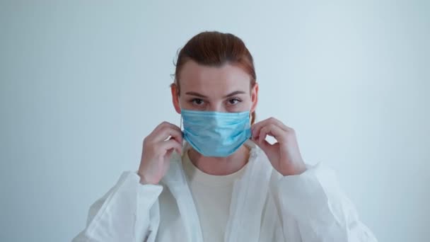 Médico en el trabajo, miembro del personal médico femenino en guantes se pone traje protector, máscara y gafas durante la pandemia debido al coronavirus para examinar a los pacientes con mala salud y síntomas de enfermedad — Vídeo de stock