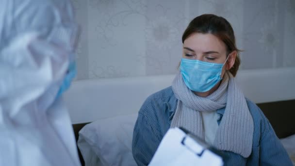 zdravotní péče, nezdravá pacientka v lékařské masce na ochranu proti virům a nemocem konzultuje lékaře v ochranném obleku, stěžuje si na špatné zdraví pravděpodobně v důsledku koronaviru