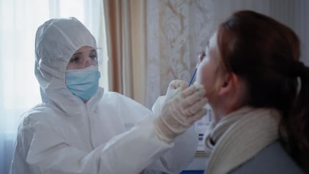 Medizin und Gesundheit: Ärztin im Schutzanzug wegen Coronavirus nimmt Test auf Virus und Infektion von junger Frau mit schlechter Gesundheit — Stockvideo