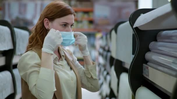 Kupující v karanténě, mladá žena v rukavicích nasadí lékařskou masku při dodržování bezpečnostních pravidel během pandemie a karantény — Stock video