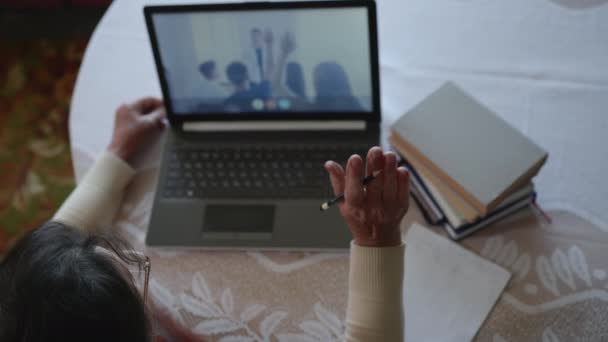 Alte Frau unterzieht sich weiteren Coachings während der Online-Ausbildung am Laptop mit moderner Technologie hebt die Hand und schreibt Antwort in Notizbuch — Stockvideo