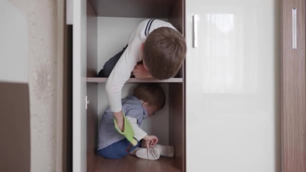 Vacances en famille, heureux petits frères amicaux aiment passer du temps ensemble et avoir du plaisir à jouer dans le placard dans la chambre — Video