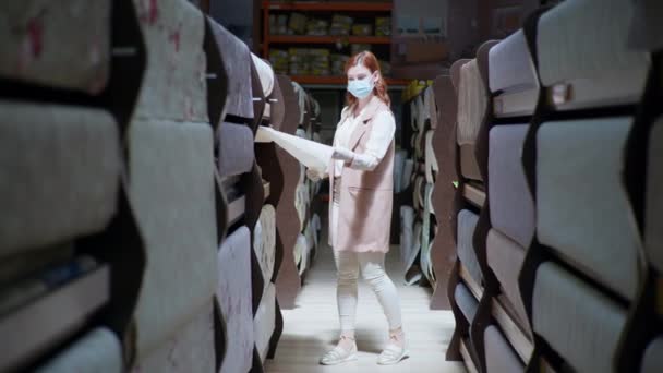 Mejora del hogar en pandemia, chica adulta en máscara médica y guantes elige fondo de pantalla para las reparaciones — Vídeos de Stock