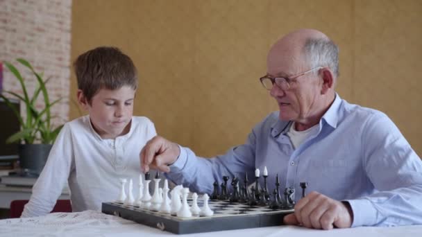 Utveckling av logiskt tänkande för barn, en intelligent farfar med glasögon för vision spelar brädspel med smart liten pojke — Stockvideo