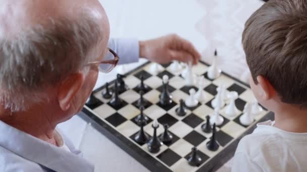 Échecs, un enfant mâle intelligent heureux joue avec son grand-père âgé aimant dans les jeux éducatifs de conseil — Video