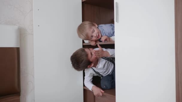 Otthon maradni, vonzó barátságos gyerekek szórakozni játszani otthon izgalmas játékok, hogy dolgozzon ki a képzelet, fiúk elrejteni a szekrényben — Stock videók