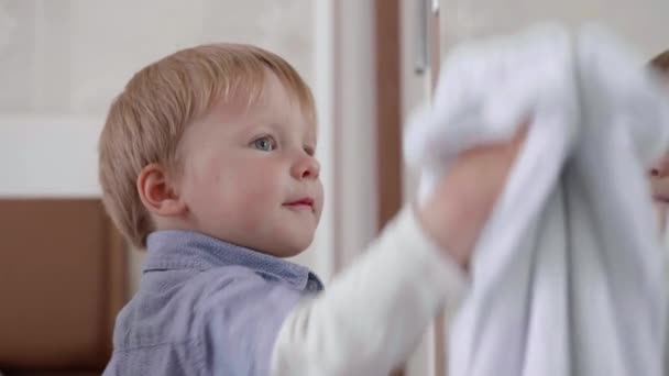 Crianças do sexo masculino cuidadores ajuda industrious com casa de limpeza e limpar espelho de sujeira com limpador e guardanapo, close-up — Vídeo de Stock