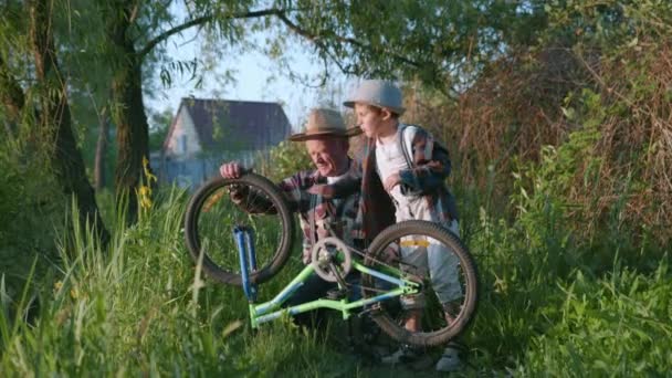 Kindheit, glücklicher Junge mit seinem Großvater beim Spazierengehen in der Natur unter Bäumen — Stockvideo