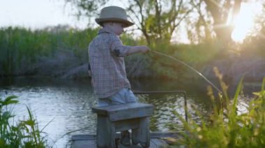 Doğadaki çocuk, şapkalı güzel bir bebek ve elinde sopayla iskelede oynarken eğleniyor.