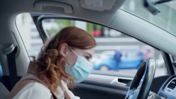 Tindakan pencegahan dalam pandemi, pengemudi perempuan yang merawat kesehatan mengenakan topeng dan kemudi untuk melindungi dari virus dan antiseptik berarti roda kemudi dan tangan di dalam mobil — Stok Video