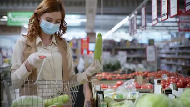 Cuarentena, hermosa mujer compradora en máscara y guantes para la protección contra virus con cesta para productos en sus manos elige verduras y frutas — Vídeos de Stock