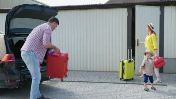 Familie weekend, vrolijke liefdevolle ouders met mannelijke kinderen plaats hun reiskoffers in de kofferbak van de auto voor treinen naar — Stockvideo