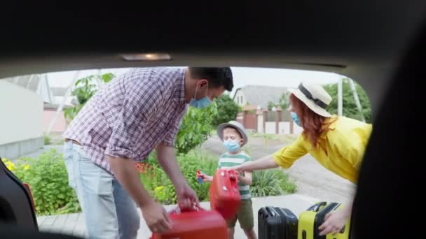 Ταξίδι του coronavirus, χαρούμενη οικογενειακή μητέρα του πατέρα και του γιου με προστατευτικές μάσκες μαζί φορτώνουν αποσκευές και ταξιδιωτικές βαλίτσες και τσάντες για ταξίδια με αυτοκίνητο — Αρχείο Βίντεο